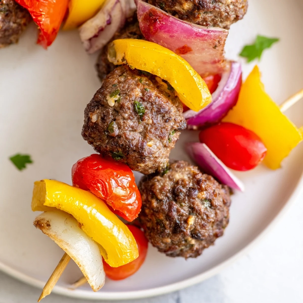 Juicy beef meatballs sizzle alongside red and yellow bell peppers on skewers, creating a colorful, easy-to-make appetizer ready for dipping.