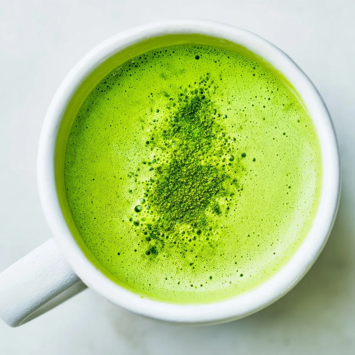 Vivid green tea latte with oat milk, prepared in a mug and frothed for a smooth, barista-style finish.