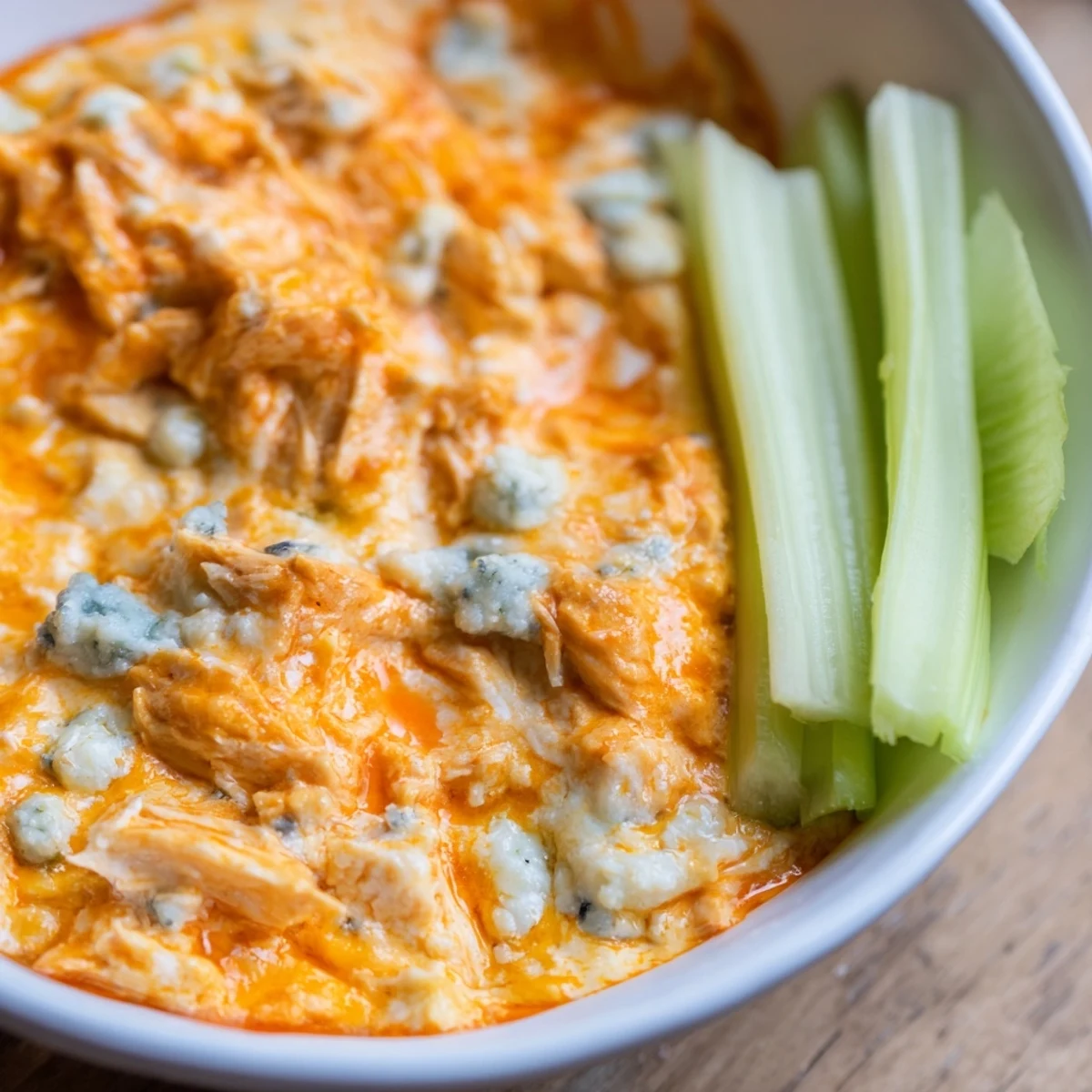 Creamy Spicy Buffalo Chicken Dip in a baking dish, topped with melted cheddar and blue cheese crumbles.