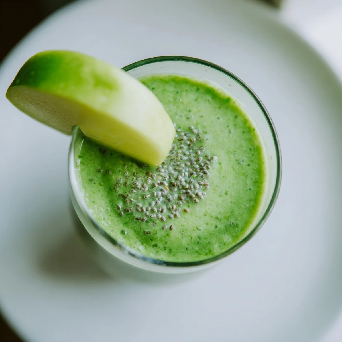 Vibrant green detox smoothie with ginger, spinach, and banana served chilled in a glass with ice.
