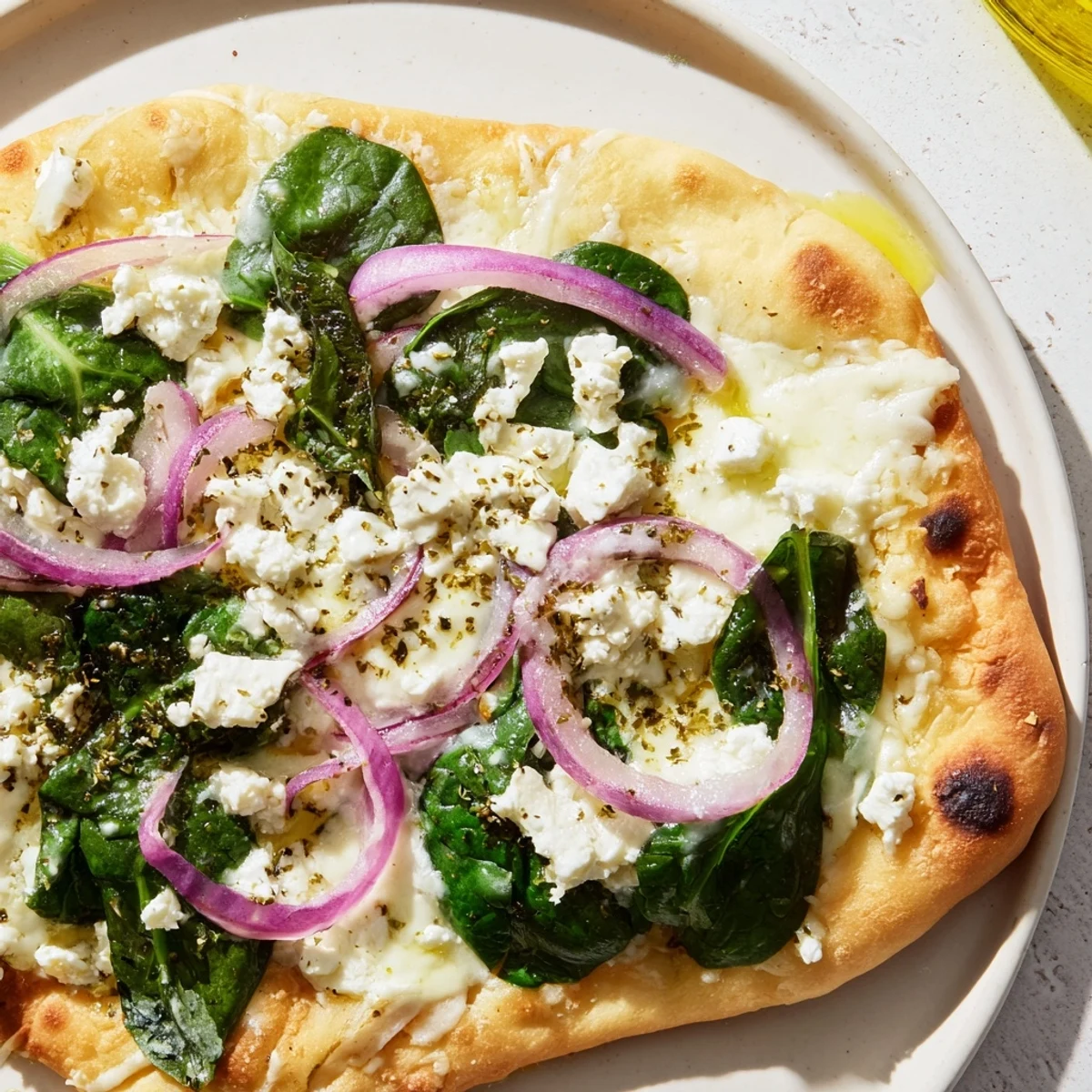 A close-up of Spinach and Feta Flatbread Pizza on a wooden board, ready to slice and serve for dinner.