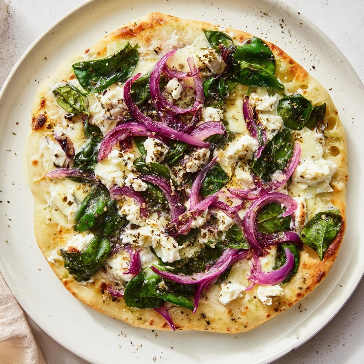 In the Spinach and Feta Flatbread Pizza, feta crumbles and red onions sit atop a warm, garlic-scented base.