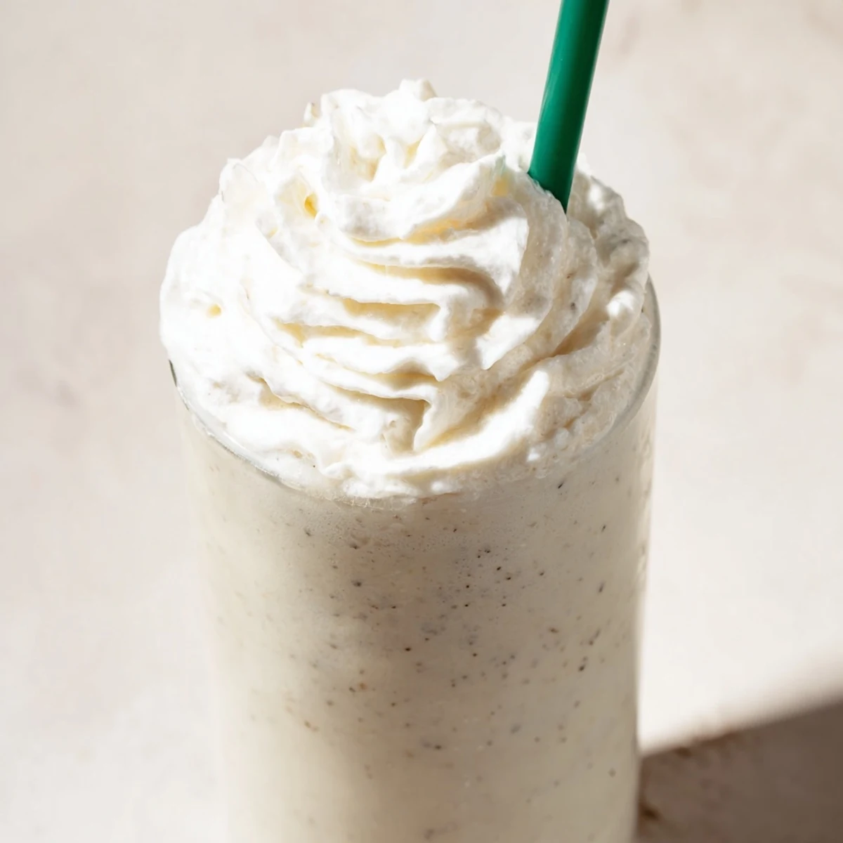 Frozen Starbucks Vanilla Bean Frappuccino with ice cubes blended smooth, served with a straw for refreshment.
