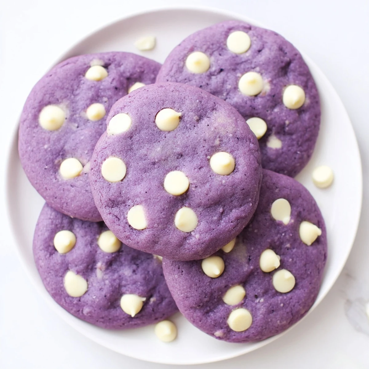 Stack of warm White Chocolate Ube Cookies with ube halaya swirl on a rustic plate.