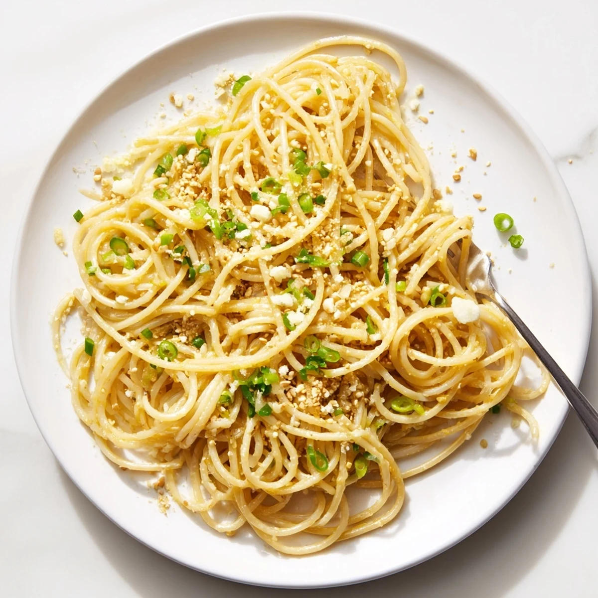 Steaming bowl of Garlic Noodles tossed in a rich garlic butter soy sauce with fresh green onions.