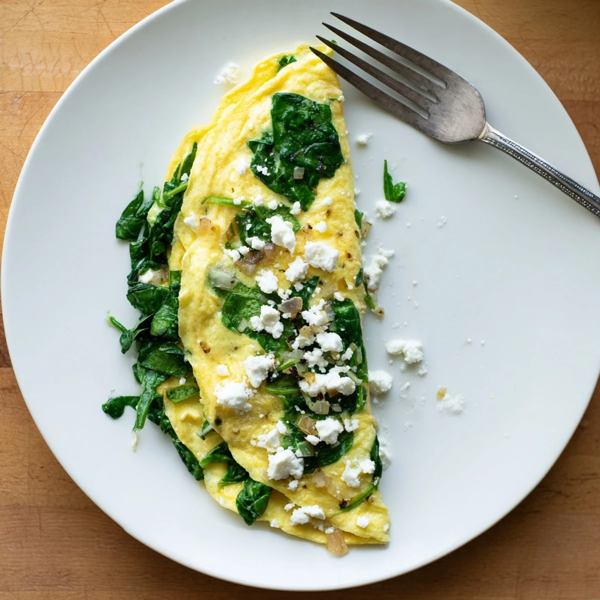 Golden-brown 15-Minute Spinach and Feta Omelet folded over creamy cheese and vibrant green spinach leaves.