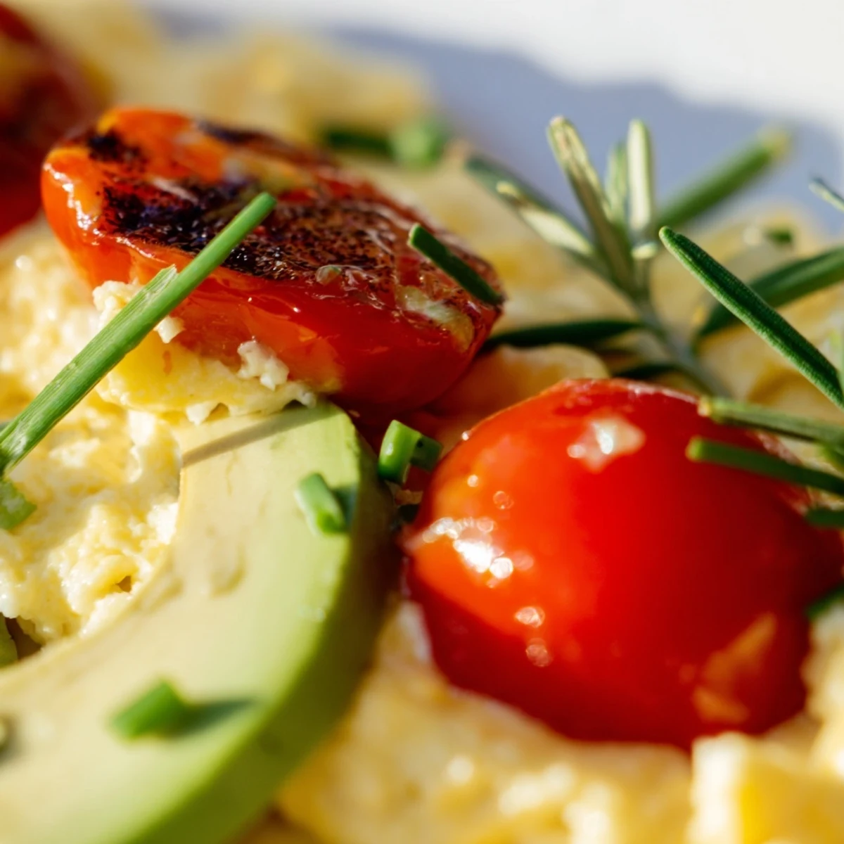 Scrambled Eggs With Avocado Seared Tomato Delight features creamy avocado slices beside golden eggs and juicy seared cherry tomatoes.