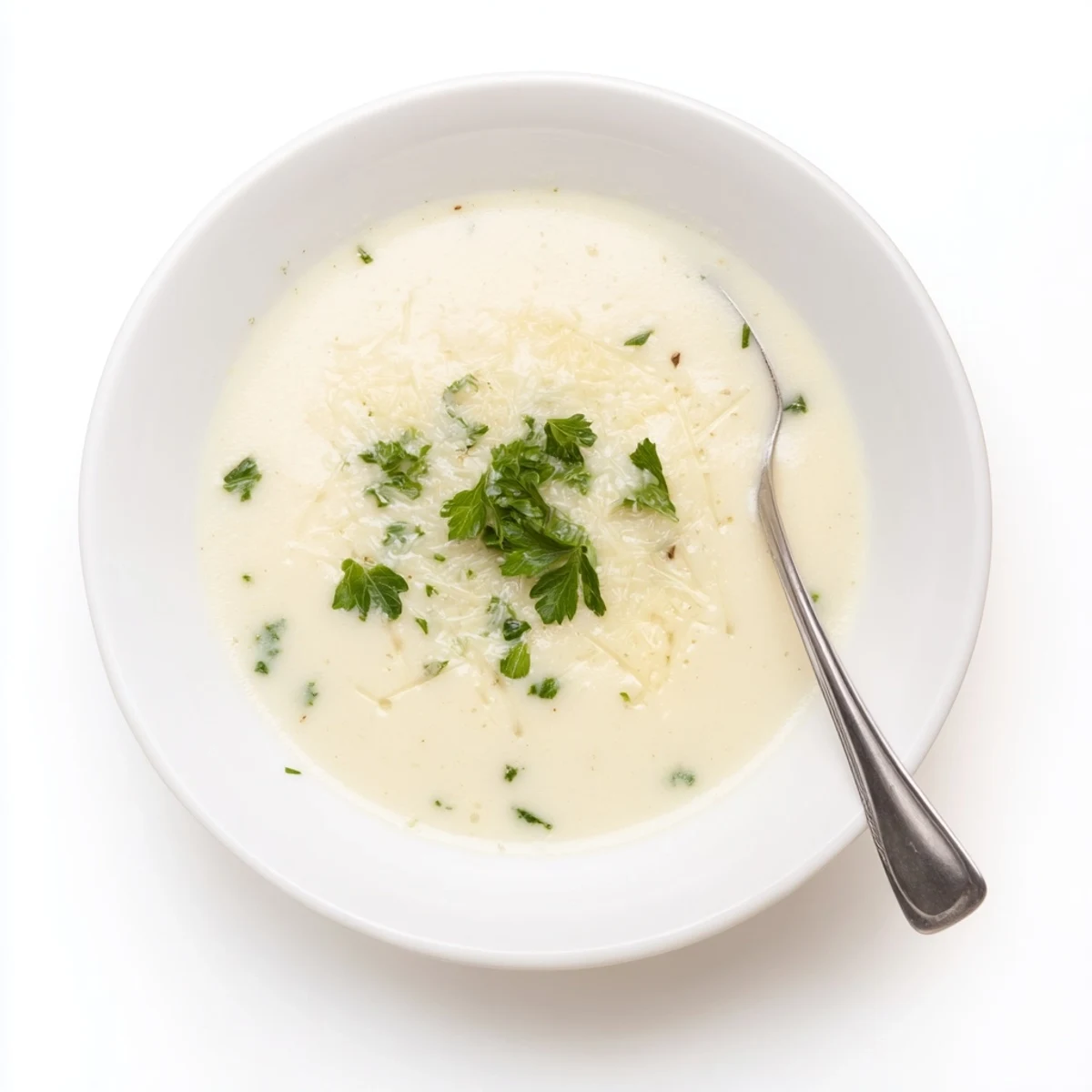 In a rustic kitchen setting, fresh cauliflower florets and whole garlic bulbs roast on a baking sheet for this savory Asiago Roasted Garlic Cauliflower Soup.