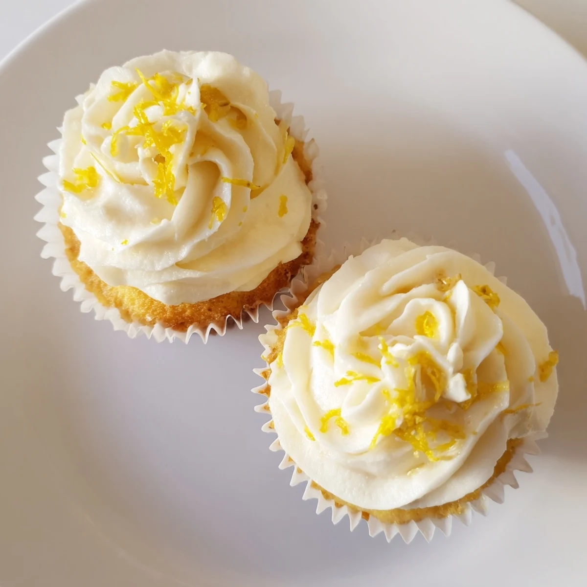 A close-up of moist Limoncello cupcakes topped with swirls of zesty frosting, ready to serve at a springtime garden party.