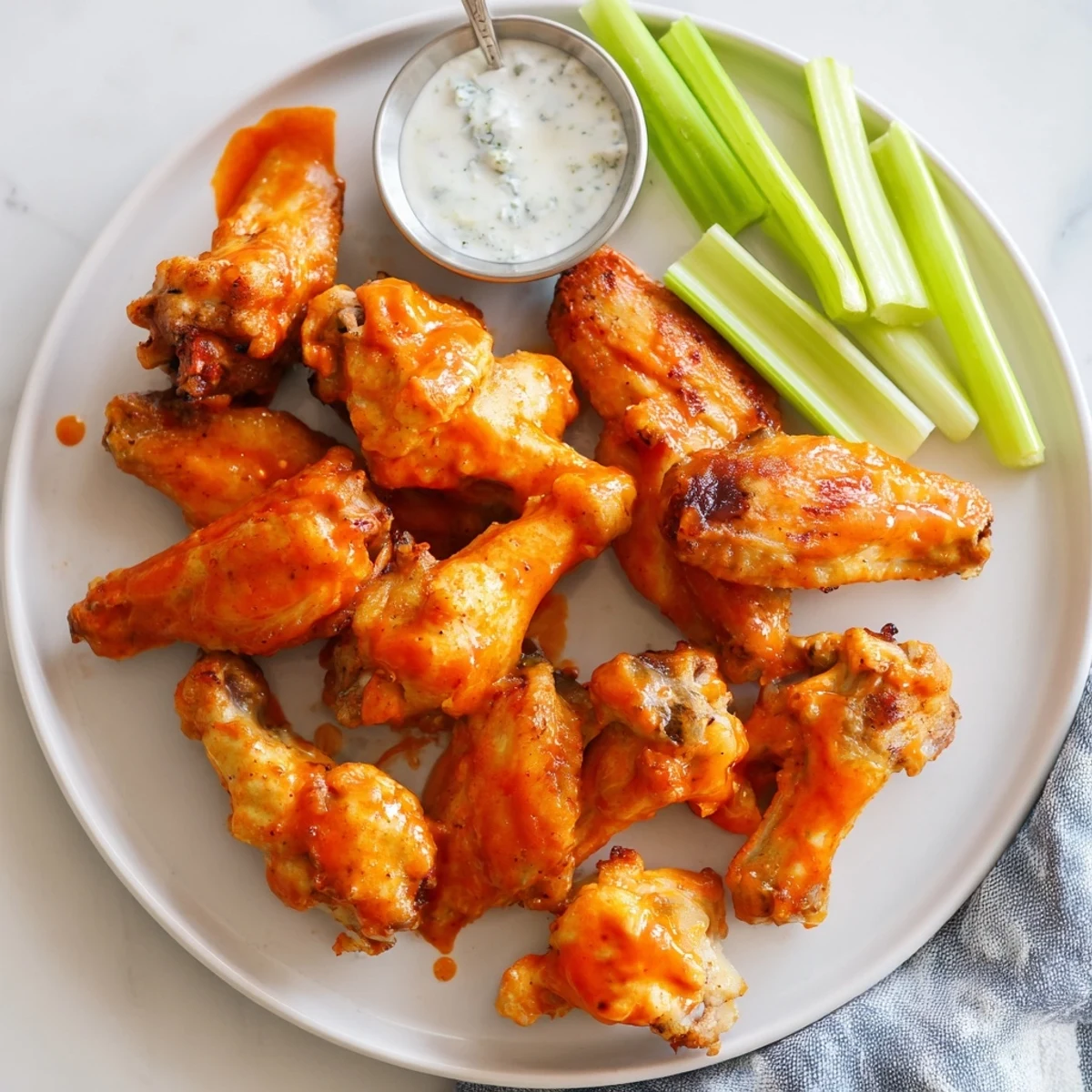 Golden-brown crispy smoked buffalo wings rest on a platter with ranch dressing for a game day snack.