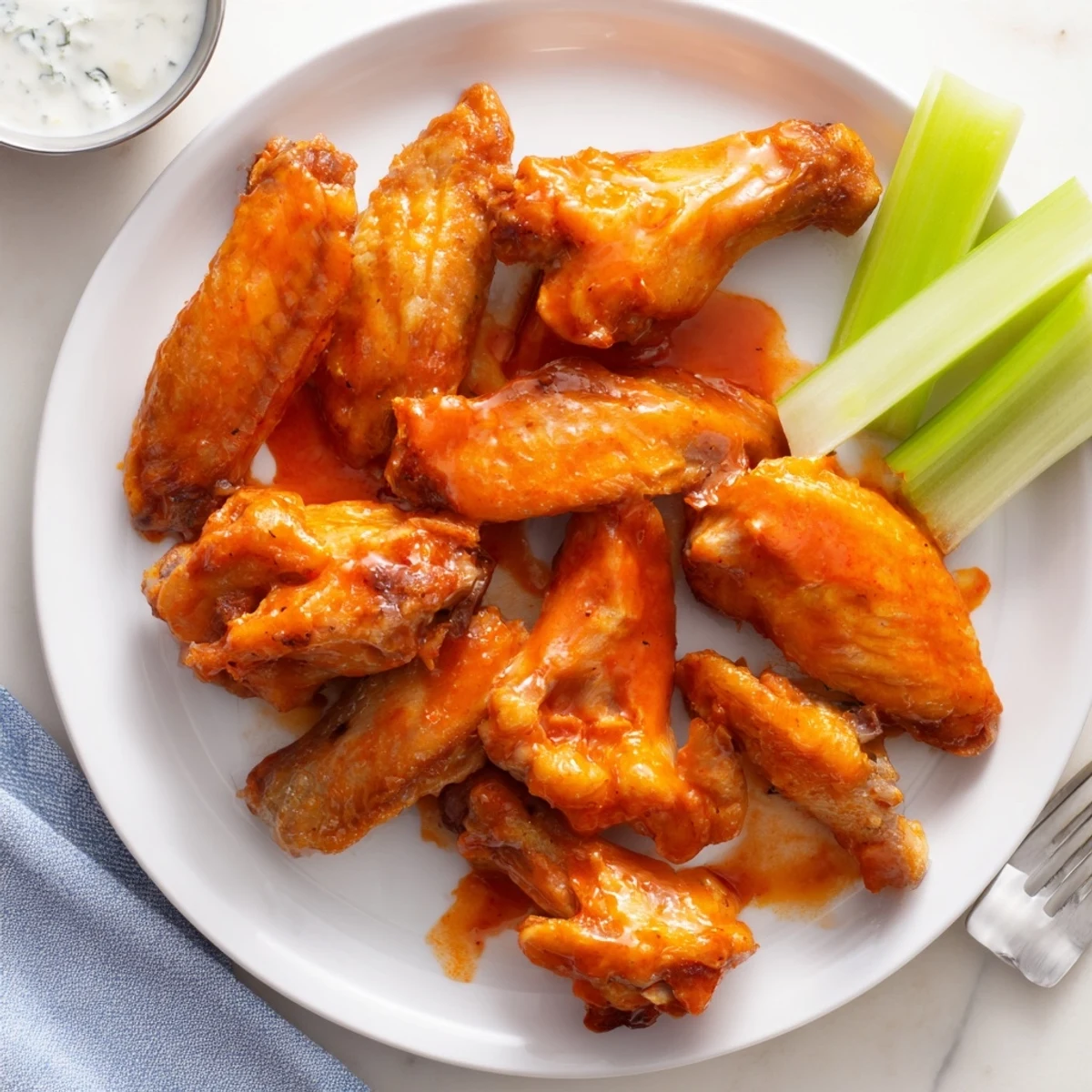 Smoky, crispy buffalo wings with a glaze of sauce, paired with fresh celery, ready to serve hot.