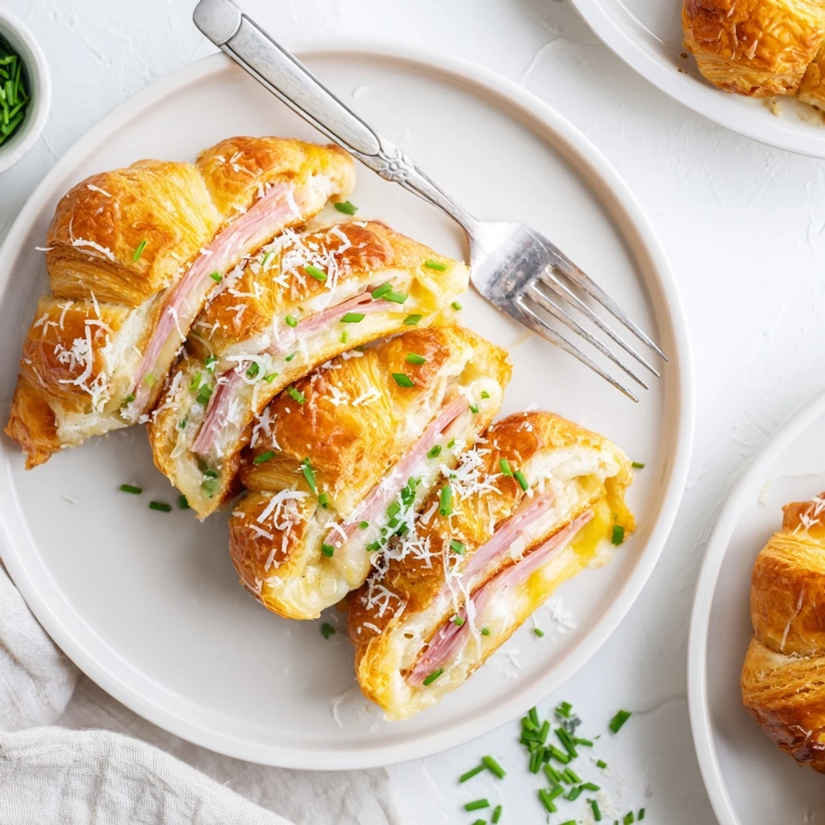 Warm baked stuffed croissants with bubbly cheese and ham, brushed with egg wash and served with fresh chives.