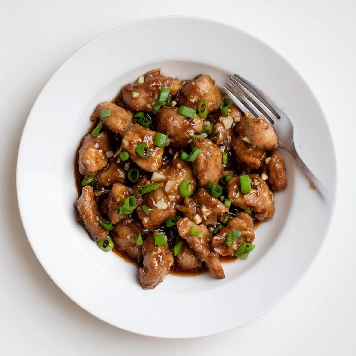 Tender bite-sized chicken thighs simmered in aromatic garlic ginger soy sauce with green onion garnish
