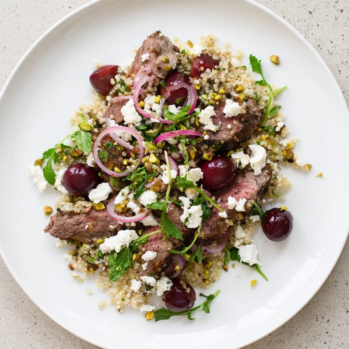 Colorful cherry quinoa salad with lamb featuring juicy red cherries, fluffy quinoa, and tender spiced meat atop fresh greens