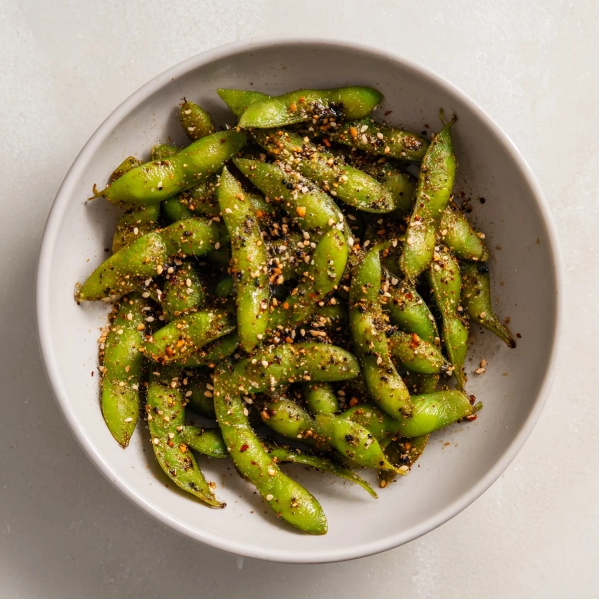 Protein-rich air fryer edamame sprinkled with sesame seeds and red chili flakes garnish