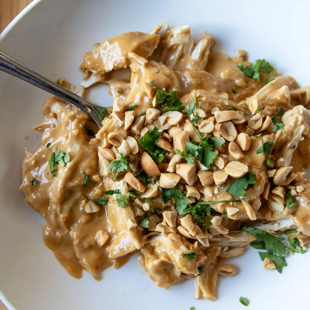 Creamy slow cooker peanut chicken dish served over steamed rice with lime wedges and vibrant red bell pepper slices