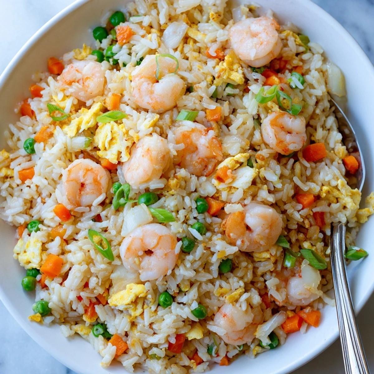 Close-up of steaming authentic shrimp fried rice with juicy shrimp, crisp vegetables, and aromatic seasonings served in a wide white bowl
