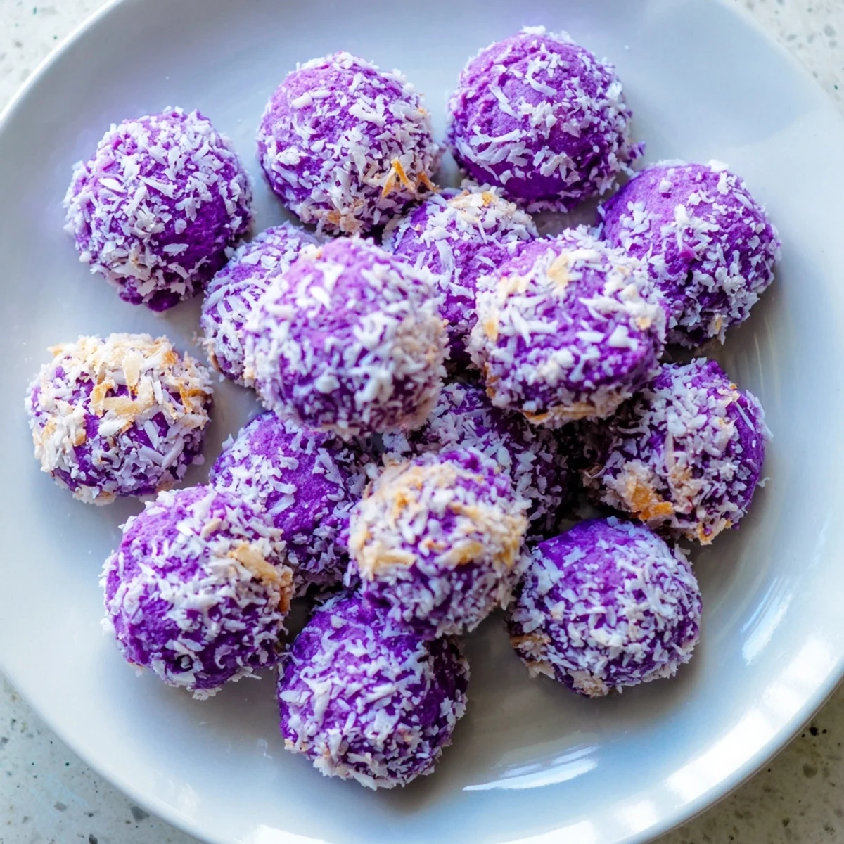A stack of bite-sized ube besito cookies topped with shredded coconut, perfect for afternoon tea or dessert sharing