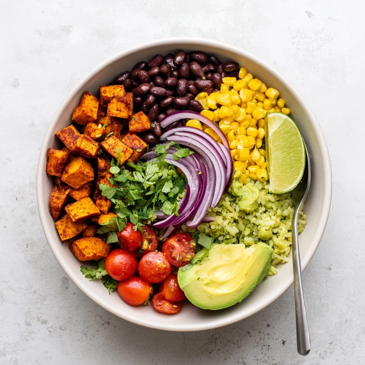 Hearty vegan sweet potato burrito bowl featuring crisp vegetables and fluffy cilantro lime rice