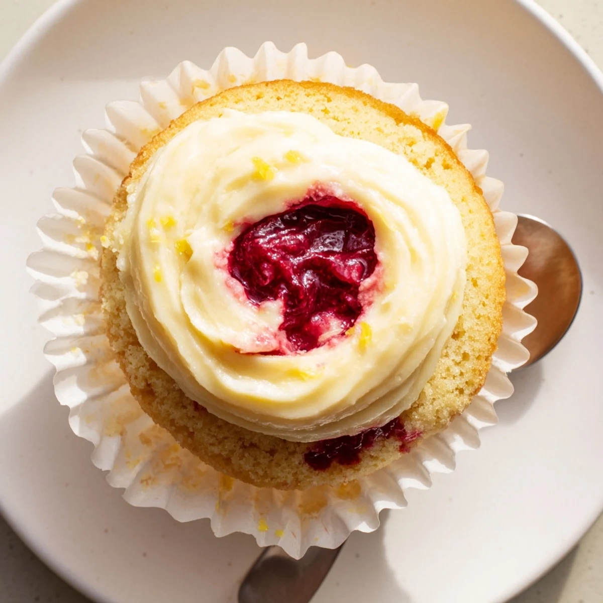 Tender moist lemon cupcakes with tangy raspberry center and creamy lemon frosting on top