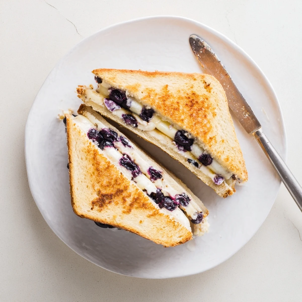 Sliced blueberry grilled cheese revealing gooey cream cheese and fresh fruit layers inside