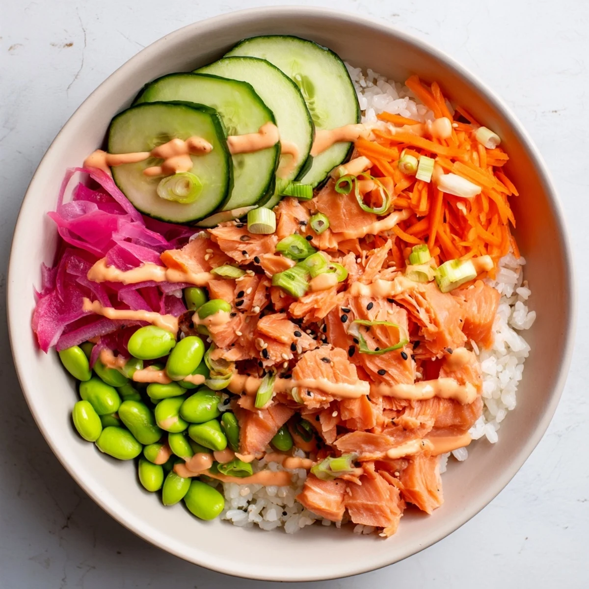 Vibrant easy salmon bowl featuring tender fish, shredded carrots, edamame and drizzled spicy mayo sauce