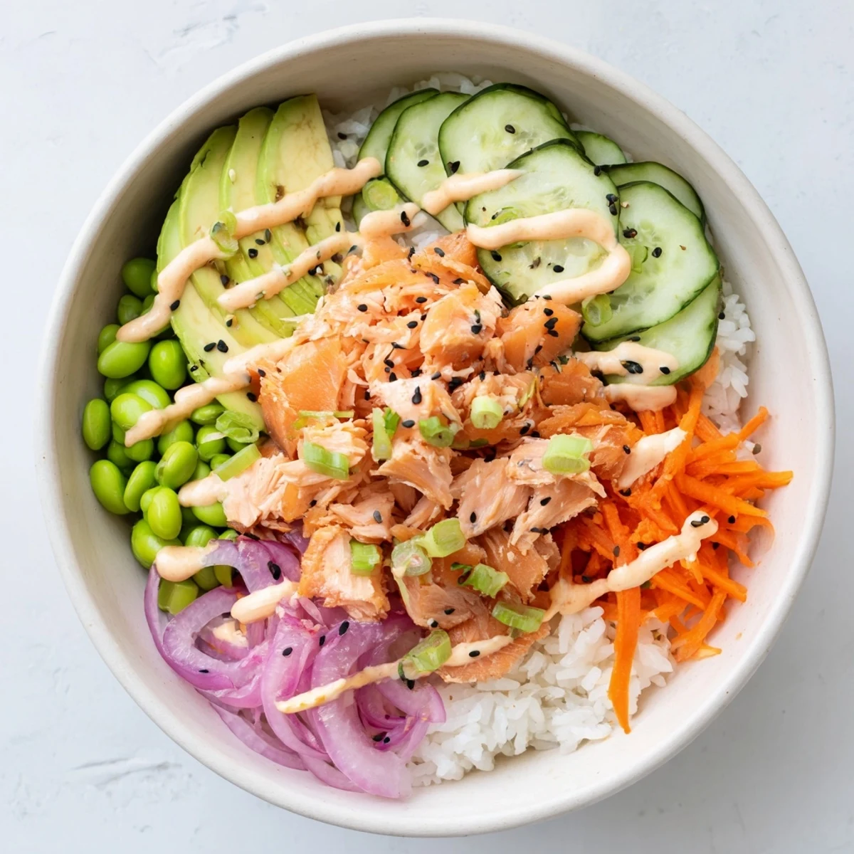 Golden baked salmon flakes atop fluffy rice with crisp cucumber and creamy avocado in an easy salmon bowl