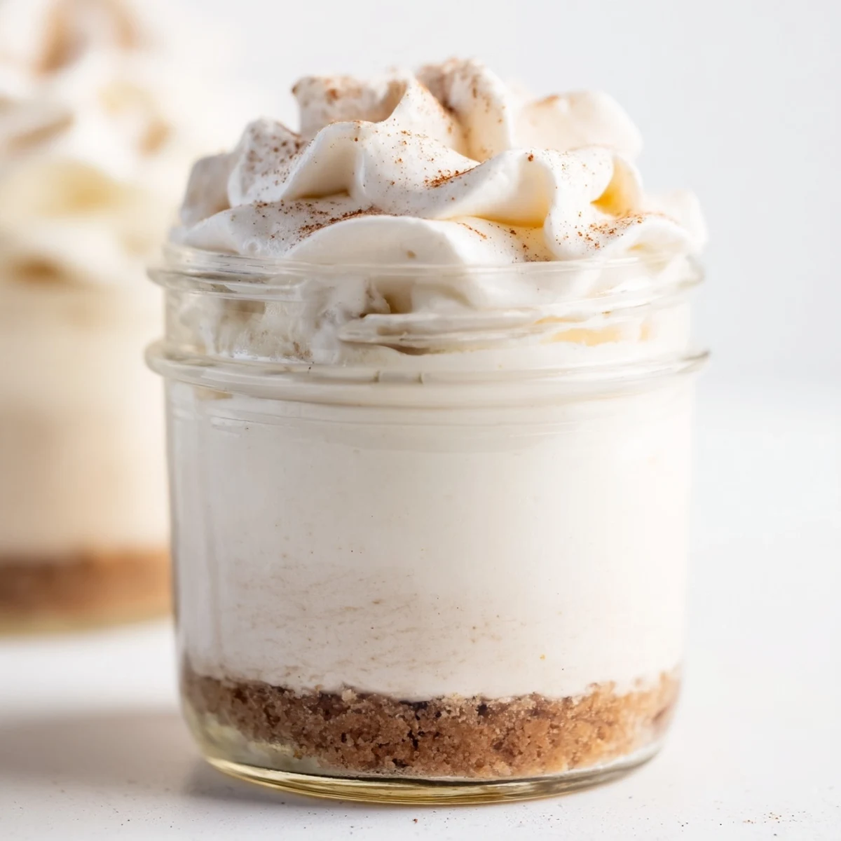 Creamy no bake mini mason jar spiced cheesecakes with graham cracker crust and whipped topping