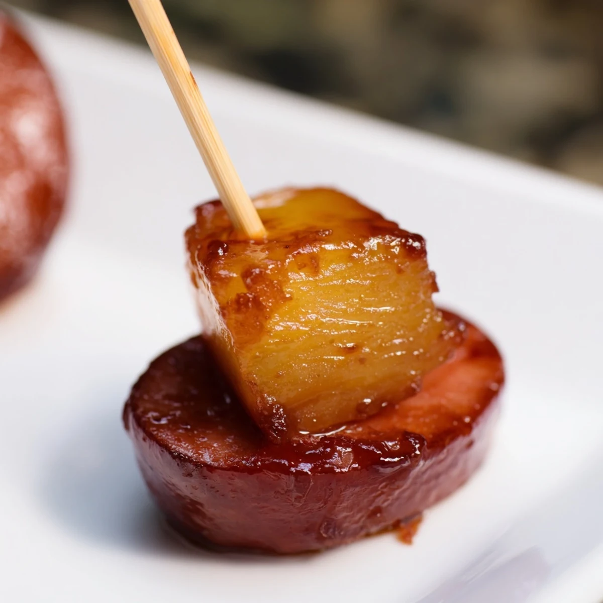 Caramelized glazed kielbasa pineapple bites glistening with sweet and savory sauce, served warm as appetizers