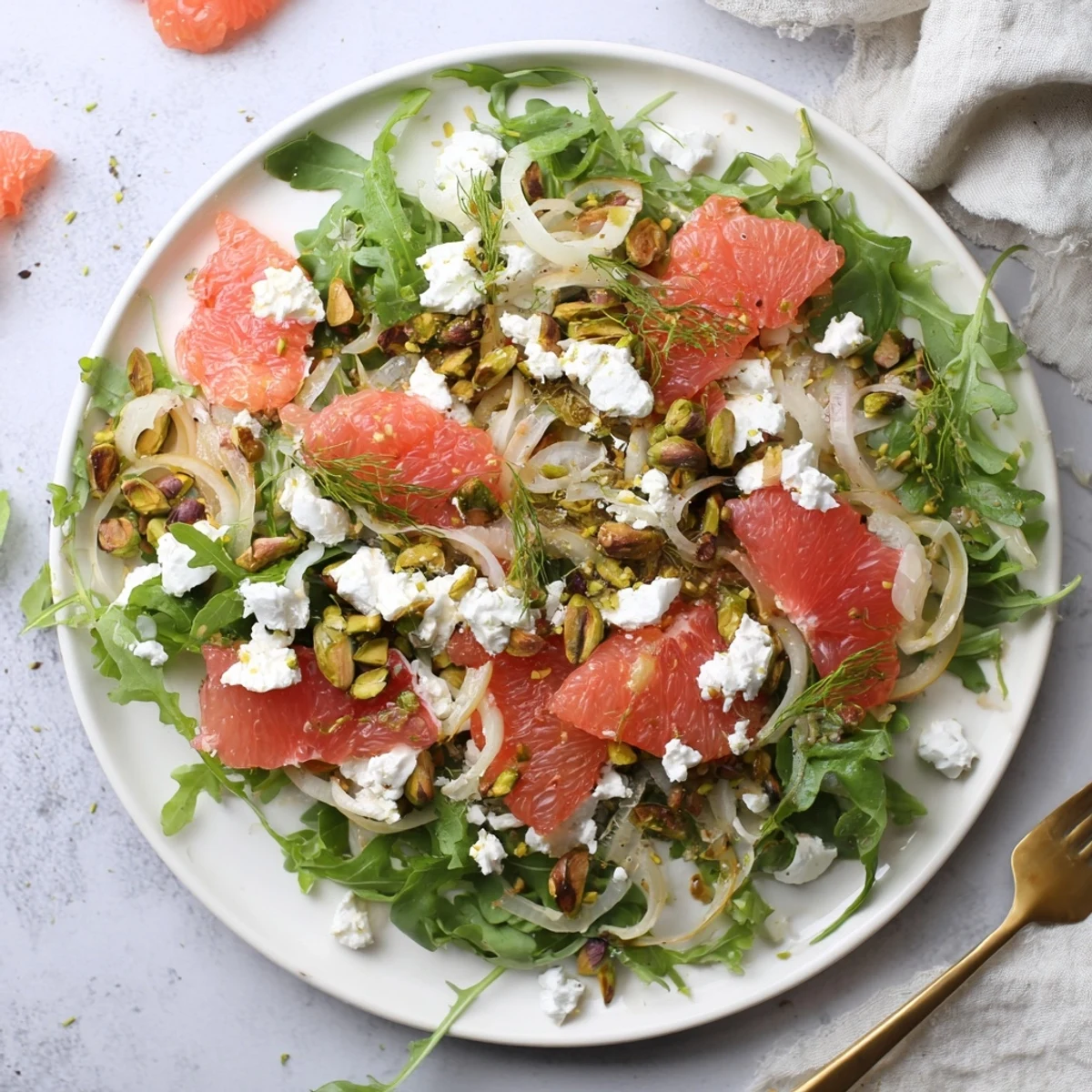 Colorful Grapefruit, Goat Cheese & Fennel Salad plated with arugula, sliced fennel bulb, grapefruit pieces, and soft cheese