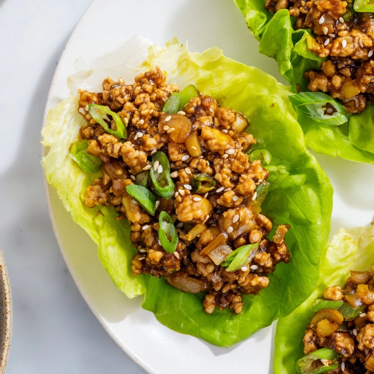 Easy chicken lettuce wraps featuring glossy saucy meat served in fresh green leaves
