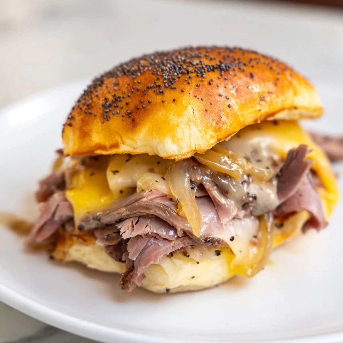 Golden French dip sliders stacked with roast beef and melted provolone cheese on Hawaiian rolls