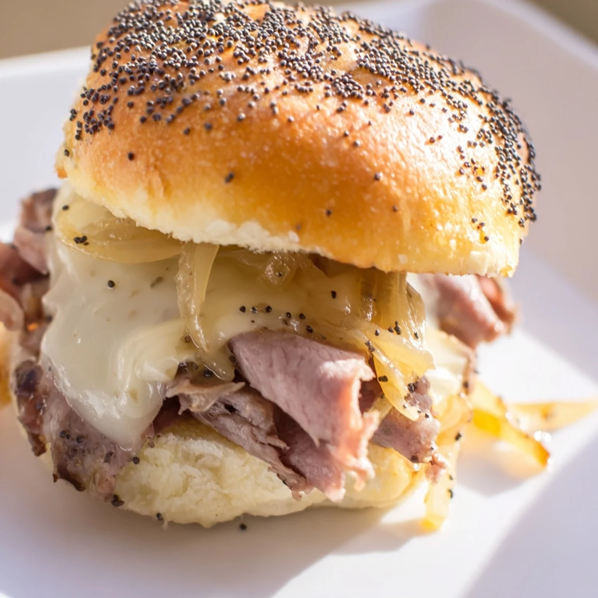 Caramelized onion French dip sliders served with rich beef au jus for dipping on a platter