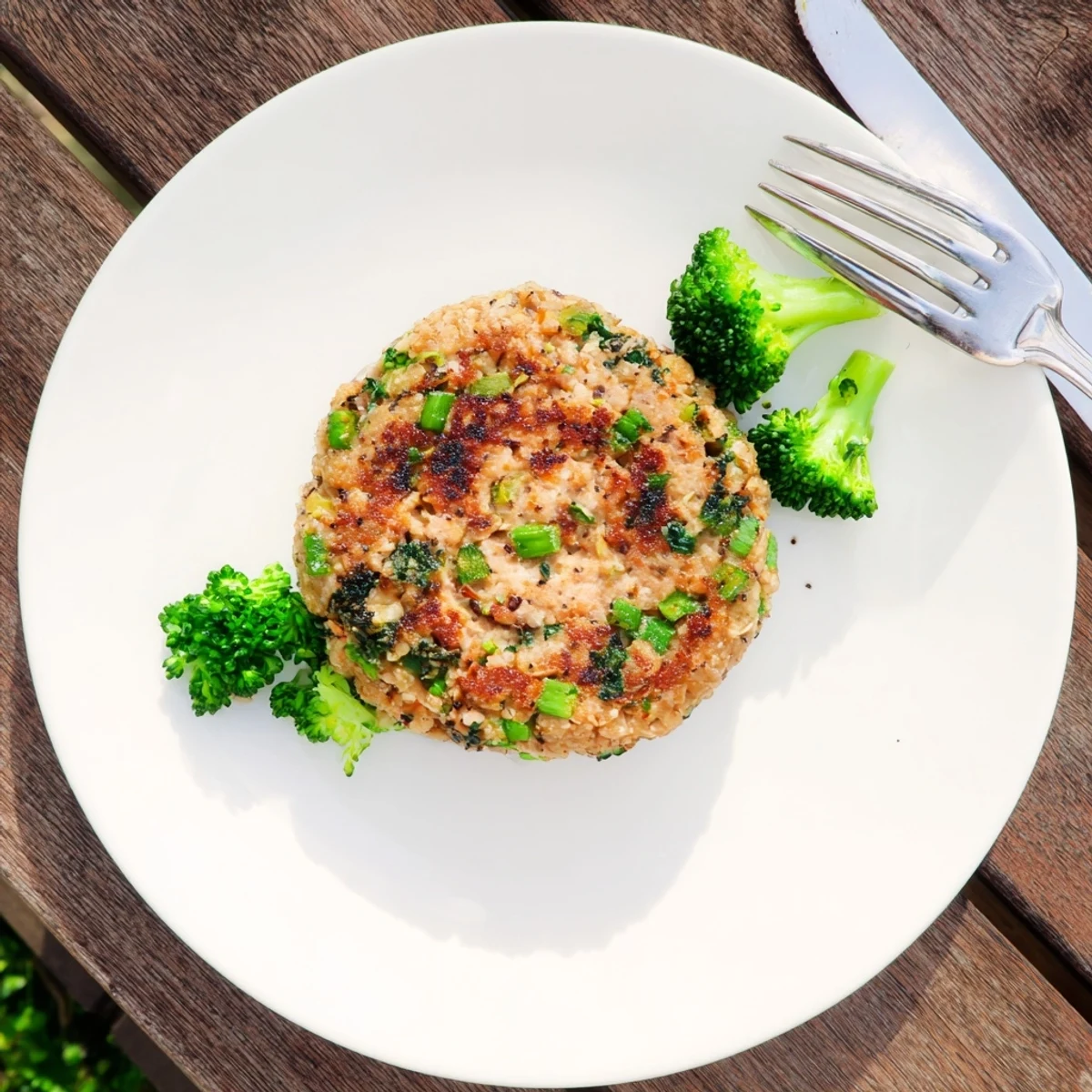Juicy healthy turkey burgers featuring tender broccoli and fluffy quinoa on a wooden serving board