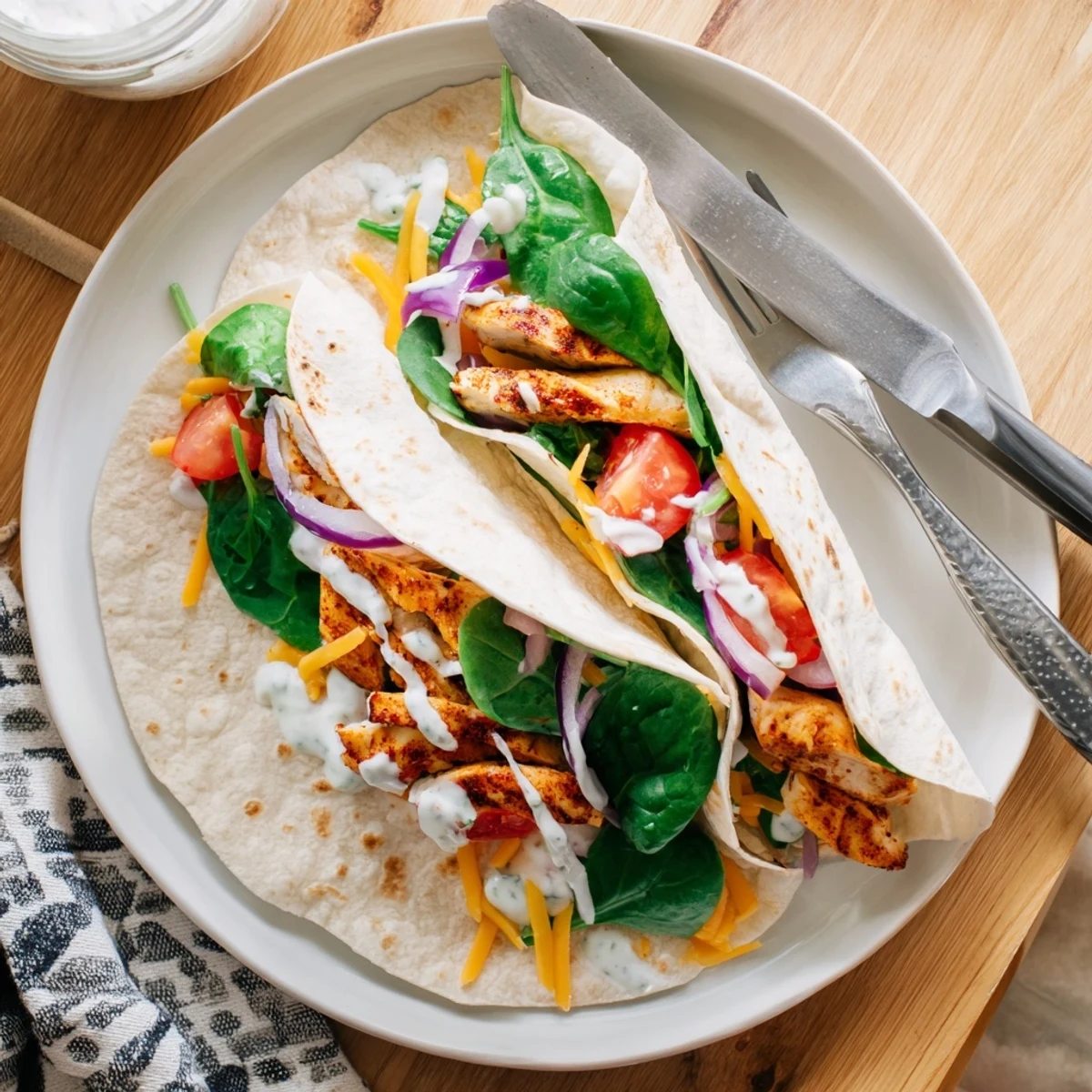 Sliced low carb chicken wrap showcasing garlic chicken, melted cheese blend, spinach, tomato, and red onion