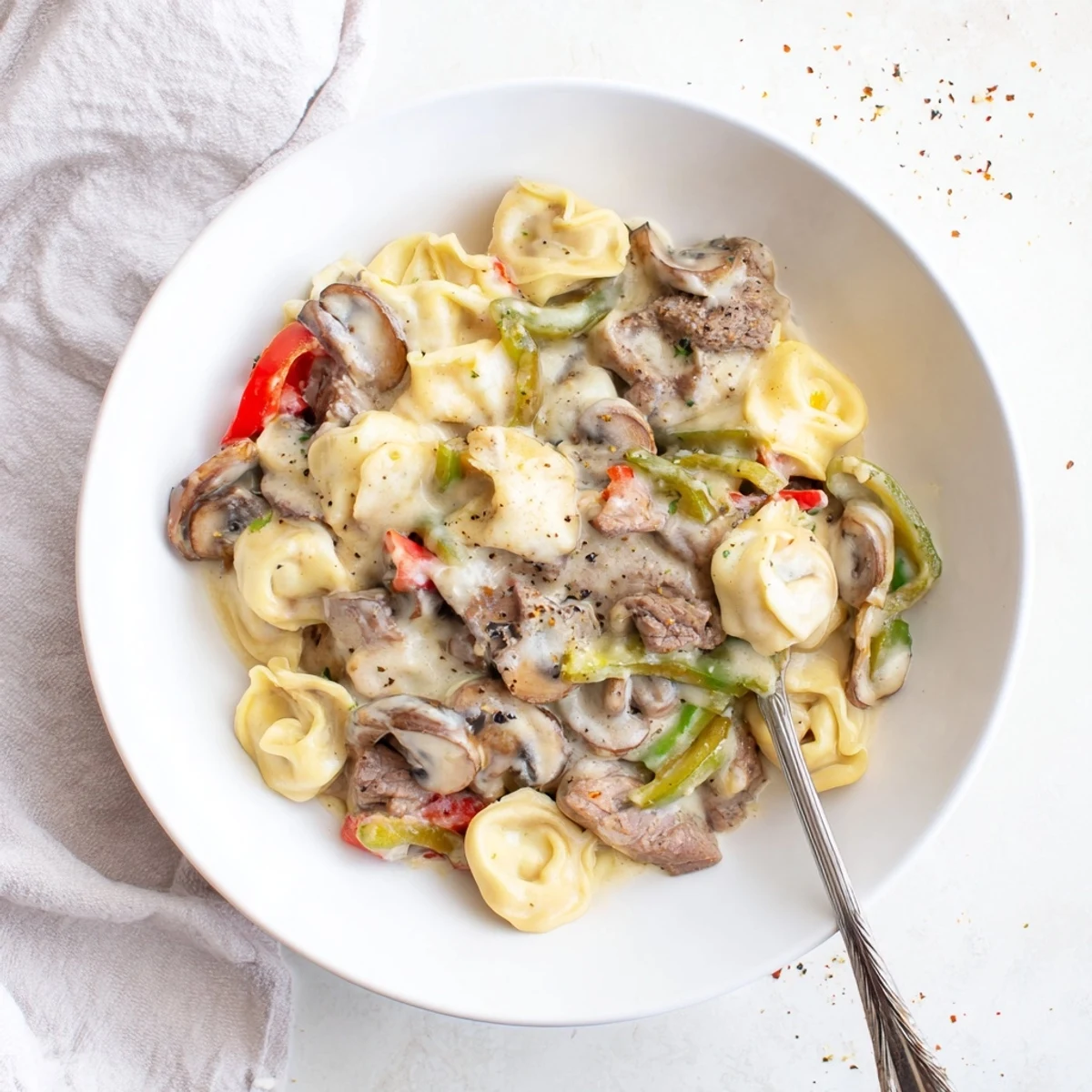 Creamy Crock Pot cheesesteak tortellini with tender beef, melted provolone, and colorful bell peppers in a rich sauce.