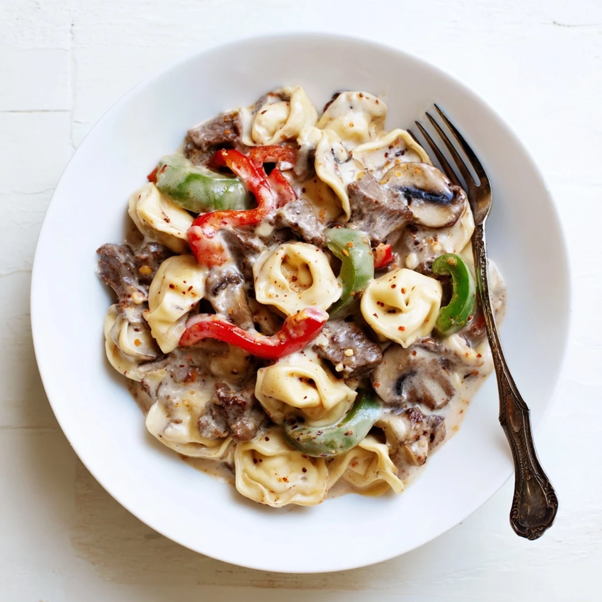 Hearty Crock Pot cheesesteak tortellini bowl loaded with beef, mushrooms, peppers, and mozzarella for a comforting family dinner.