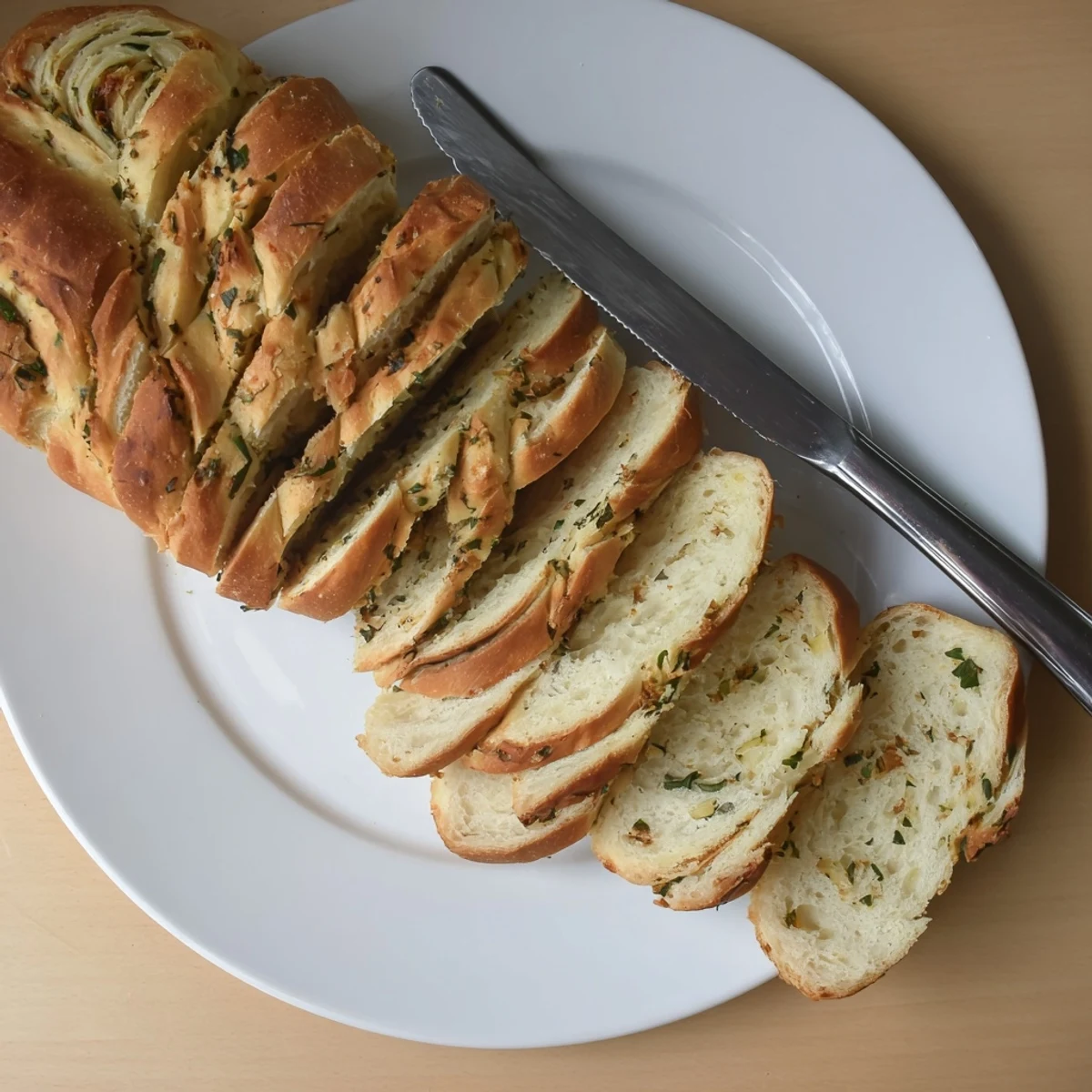 Sliced garlic and herb bread loaf showing soft interior flecked with fresh parsley and rosemary