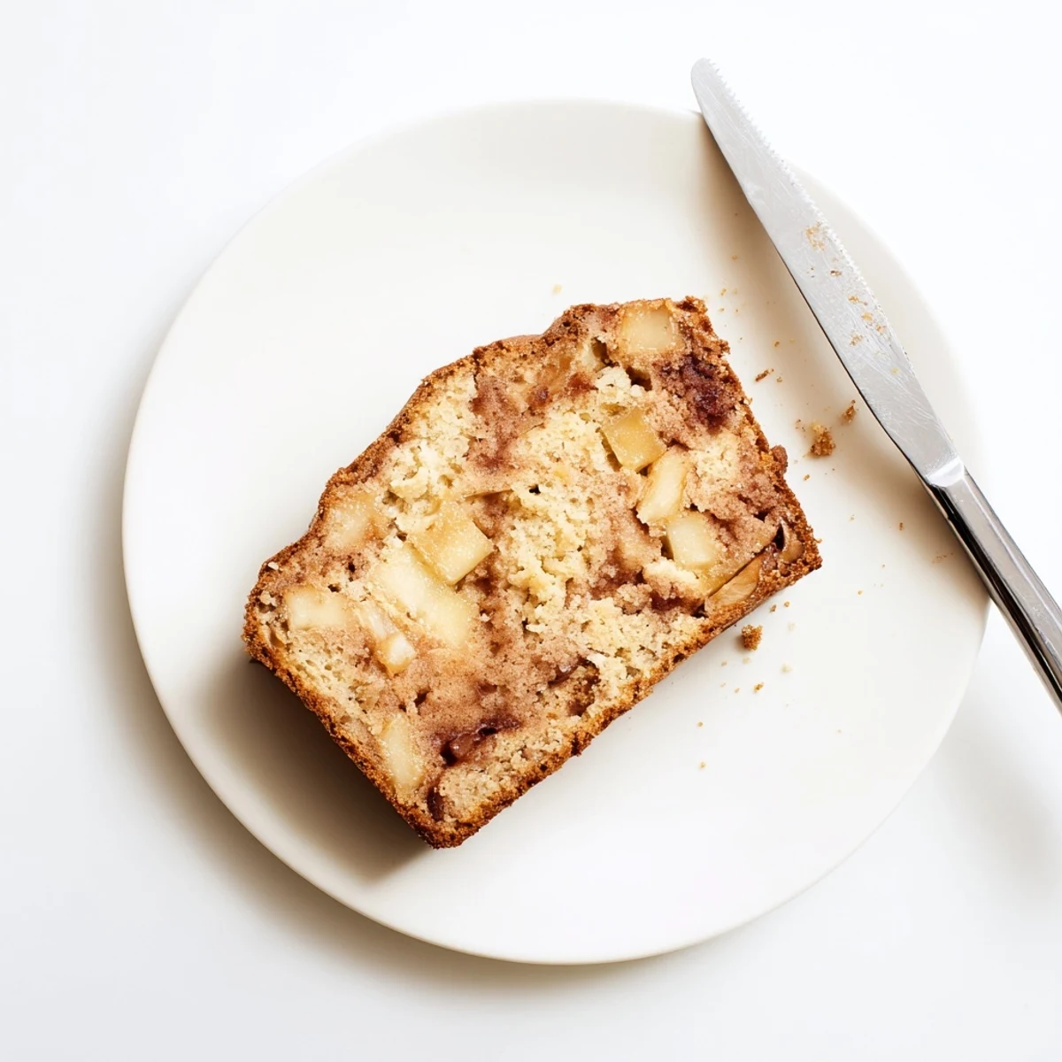 Golden cinnamon apple bread loaf with visible apple chunks and cinnamon sugar swirl topping