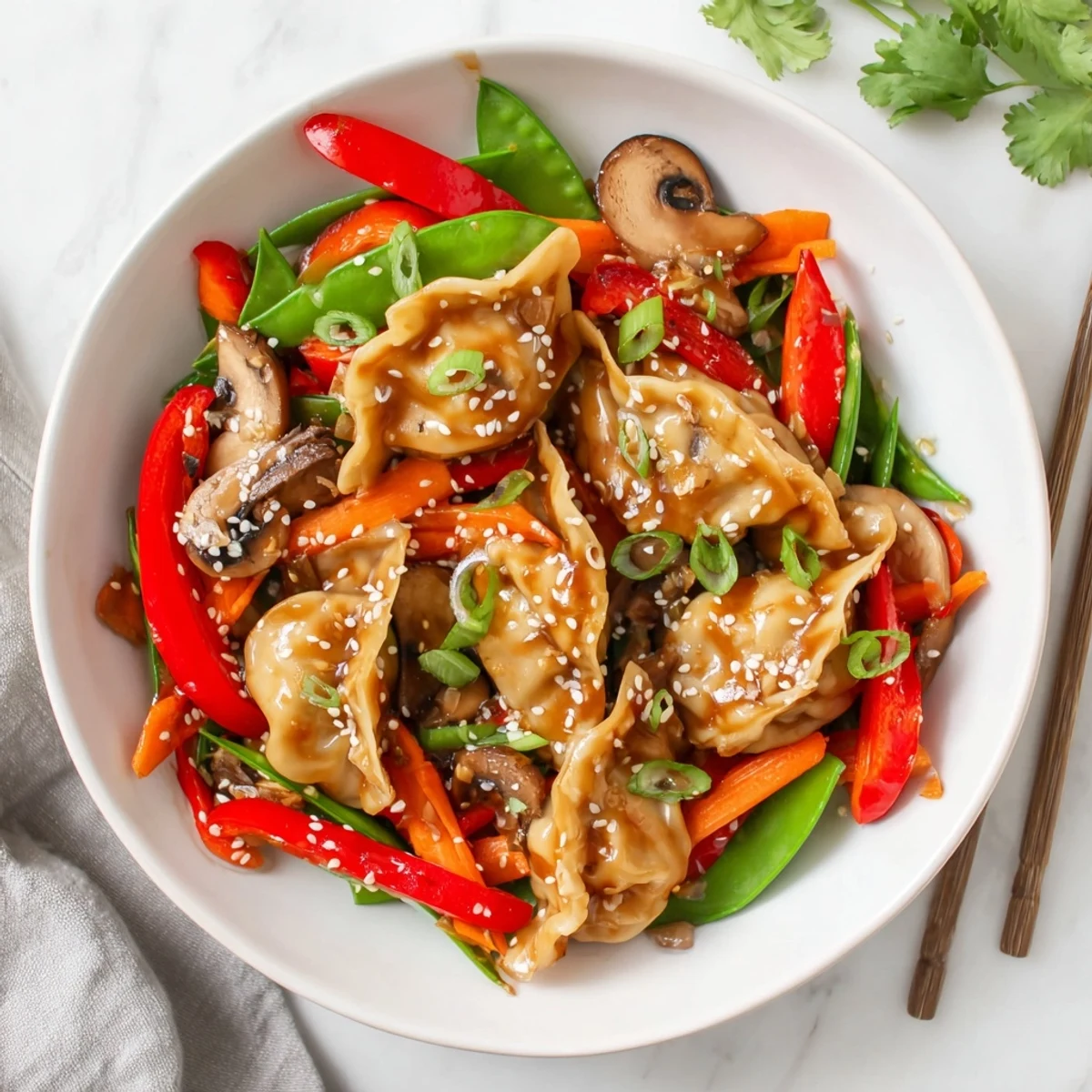 Plate of potsticker stir fry garnished with sesame seeds and fresh cilantro