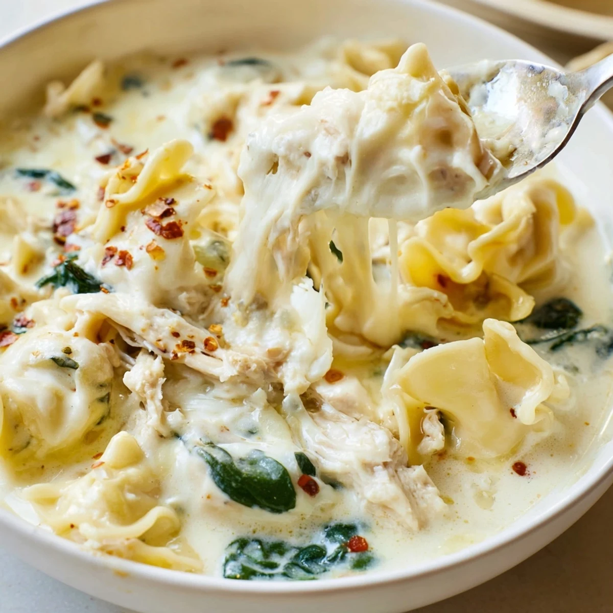 Steaming bowl of white lasagna soup topped with grated Parmesan and cracked pepper