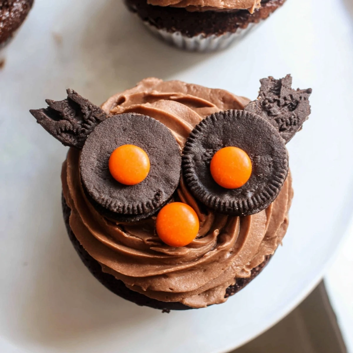 Adorable Oreo Owl Cupcakes topped with creamy chocolate frosting and cute candy eyes on a rustic baking sheet.