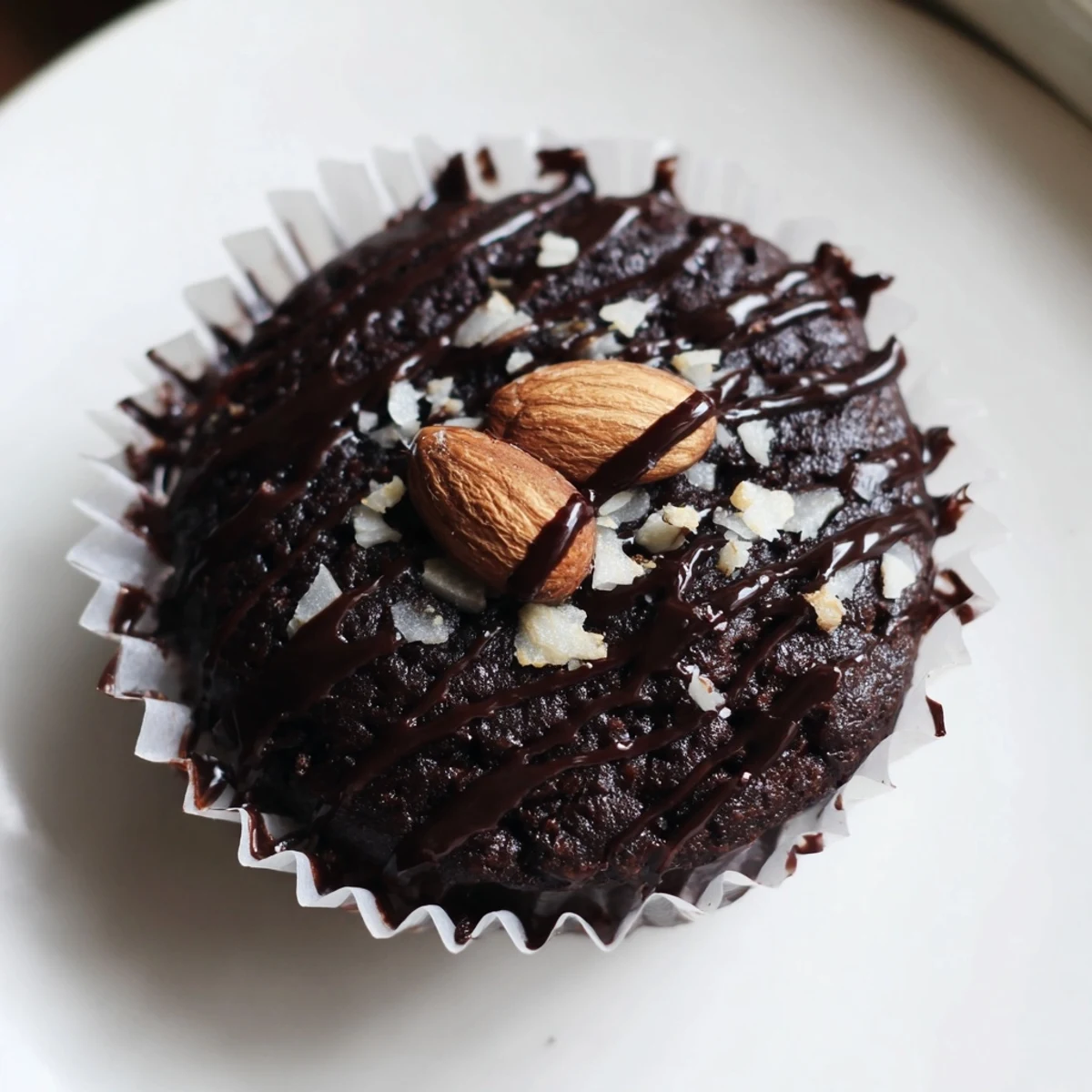 Rich flourless almond joy cupcakes topped with chocolate drizzle and roasted almonds on rustic parchment