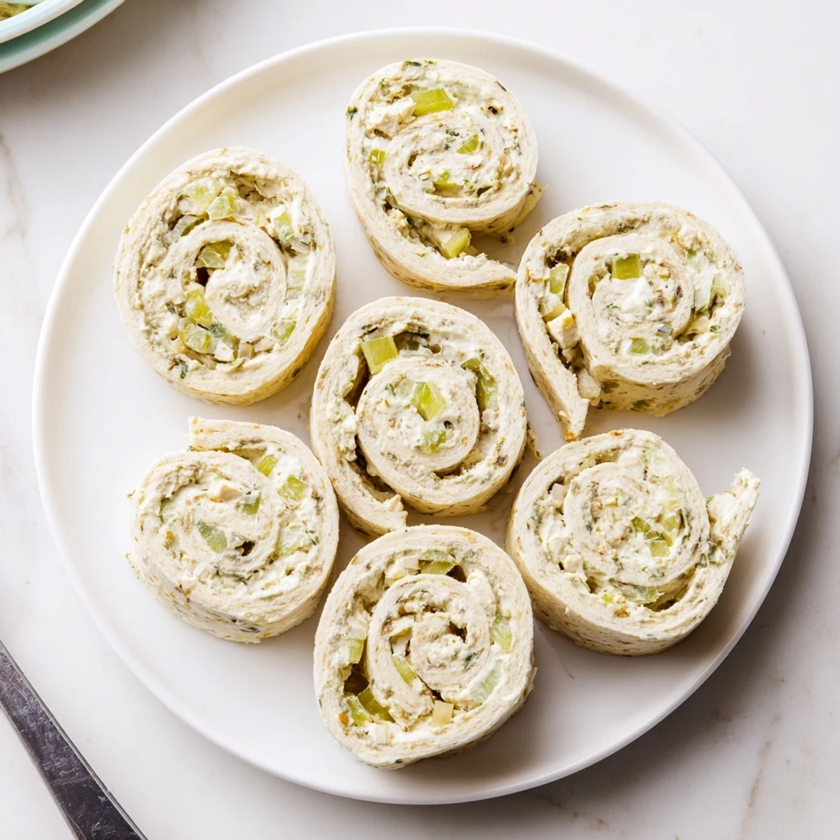 Sliced Pickle Dip Pinwheels showing cream cheese swirl, served with crunchy crackers