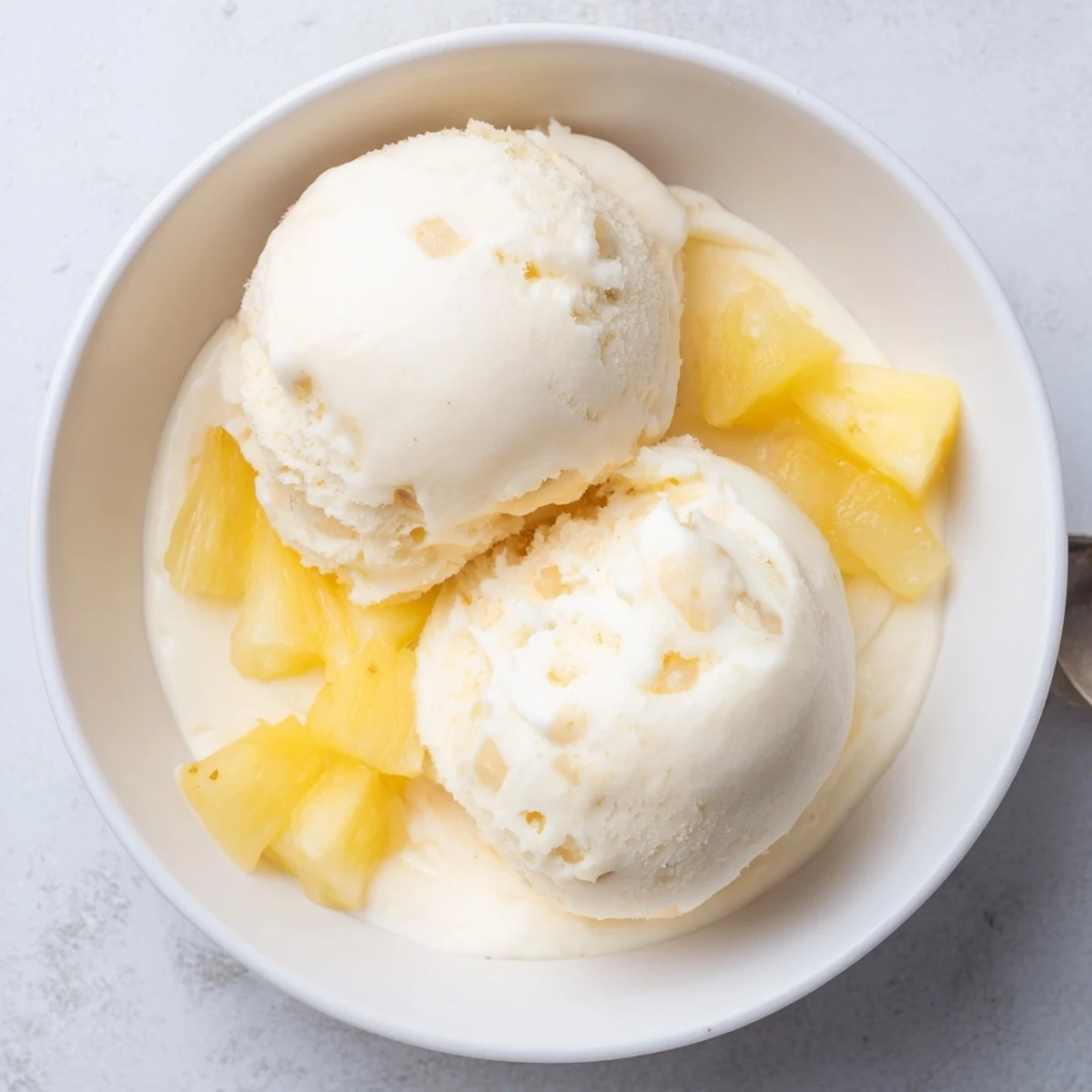Homemade Creamy Pineapple Ice Cream served in bowl with toasted coconut topping