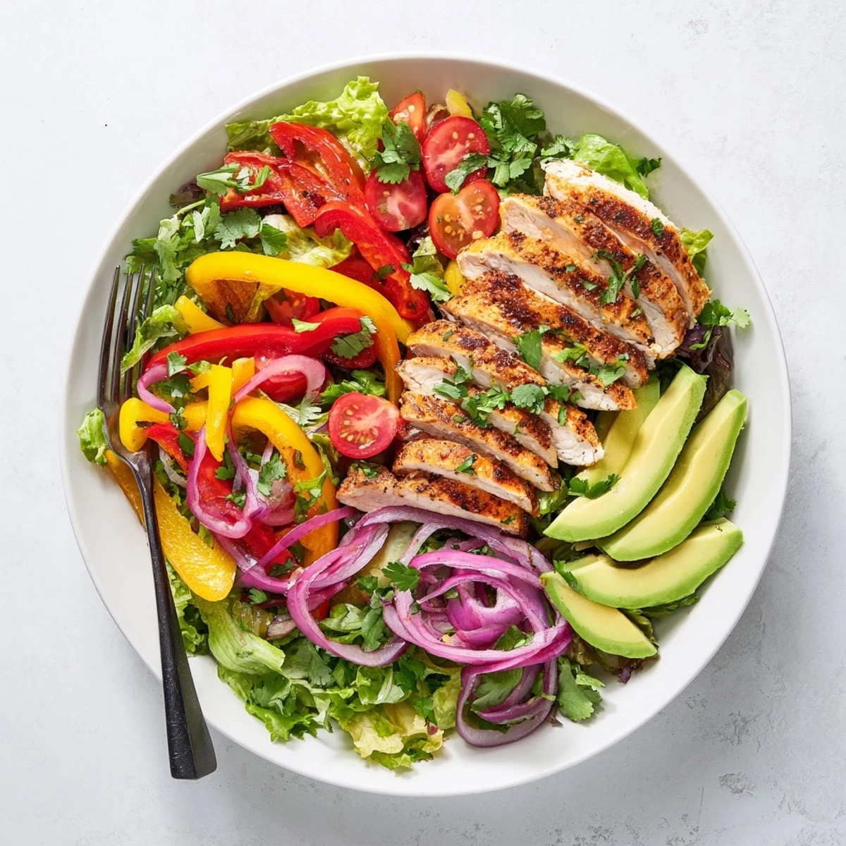 Healthy grilled chicken fajita salad plated with red peppers, avocado, and juicy spiced strips