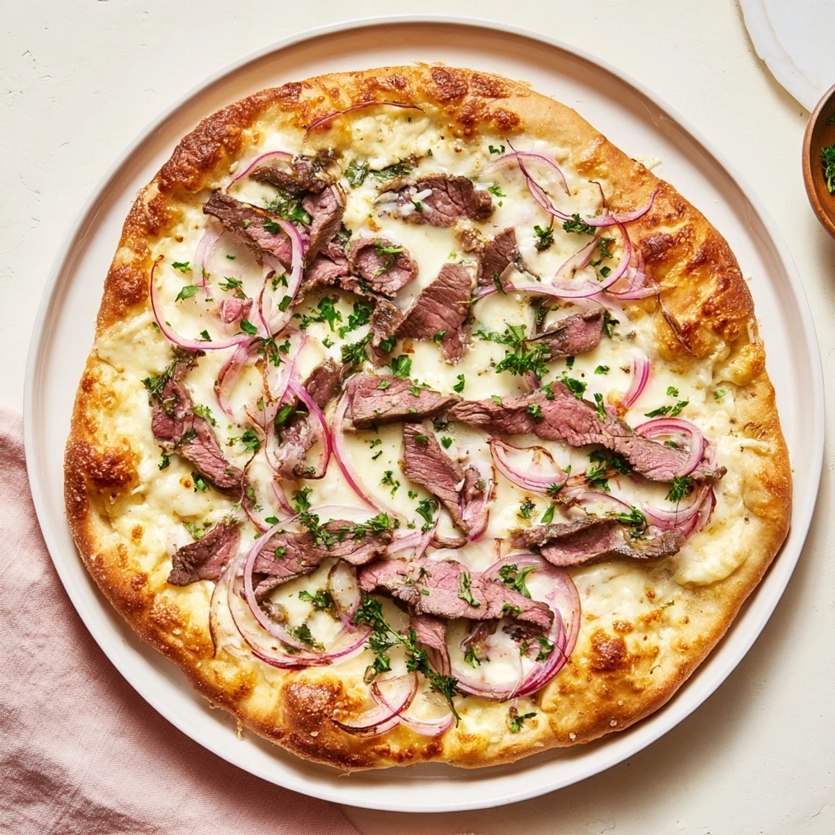 Golden Beef Alfredo Pizza with bubbling mozzarella, sliced sirloin, and fresh parsley garnish