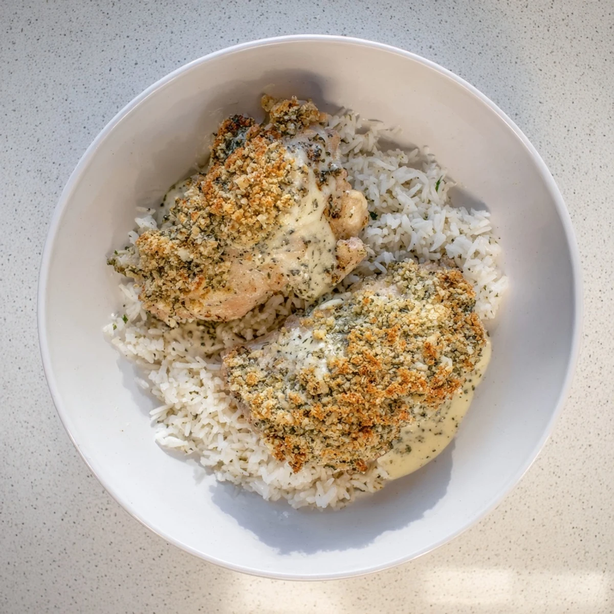 Crispy baked chicken thighs with aromatic herbs resting in velvety garlic sauce beside rice