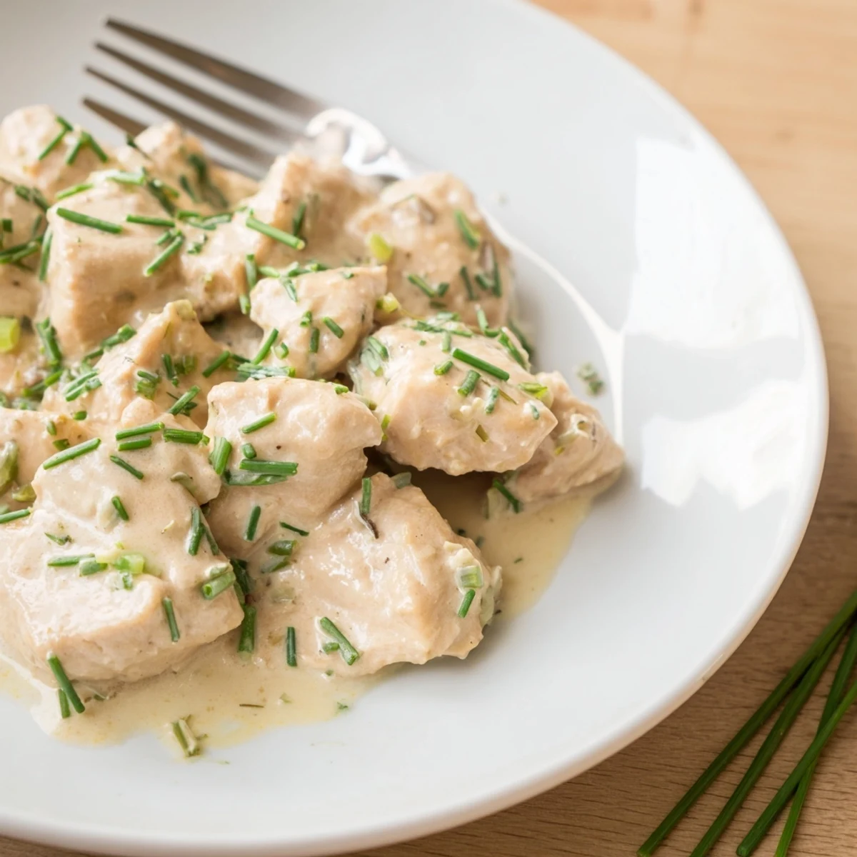 Creamy cream cheese chicken in a golden skillet topped with fresh green chives