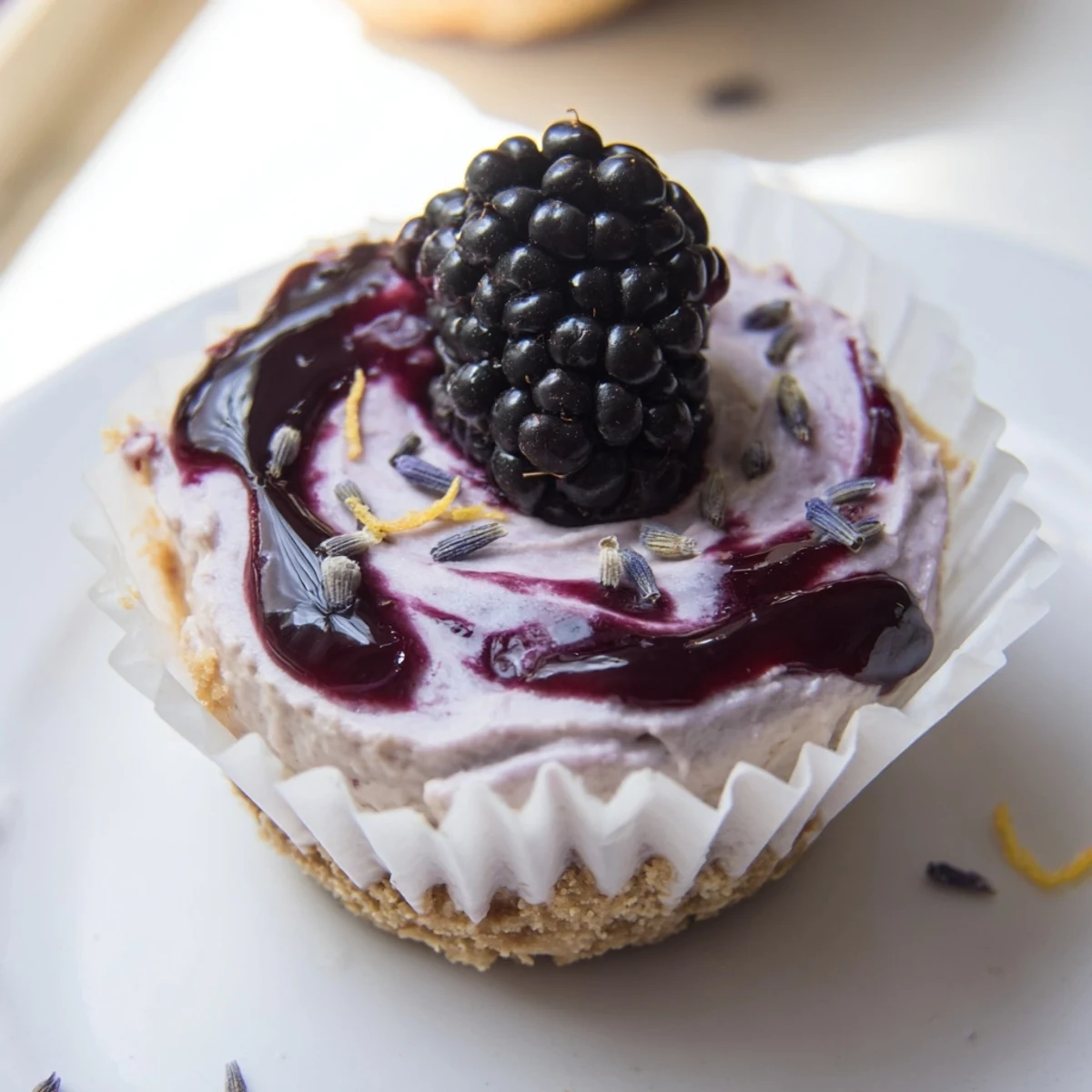 Individual no bake mini blackberry lavender cheesecakes with whipped filling and purple fruit drizzle